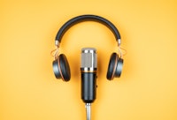 podcasting concept, directly above view of headphones and recording microphone on orange background