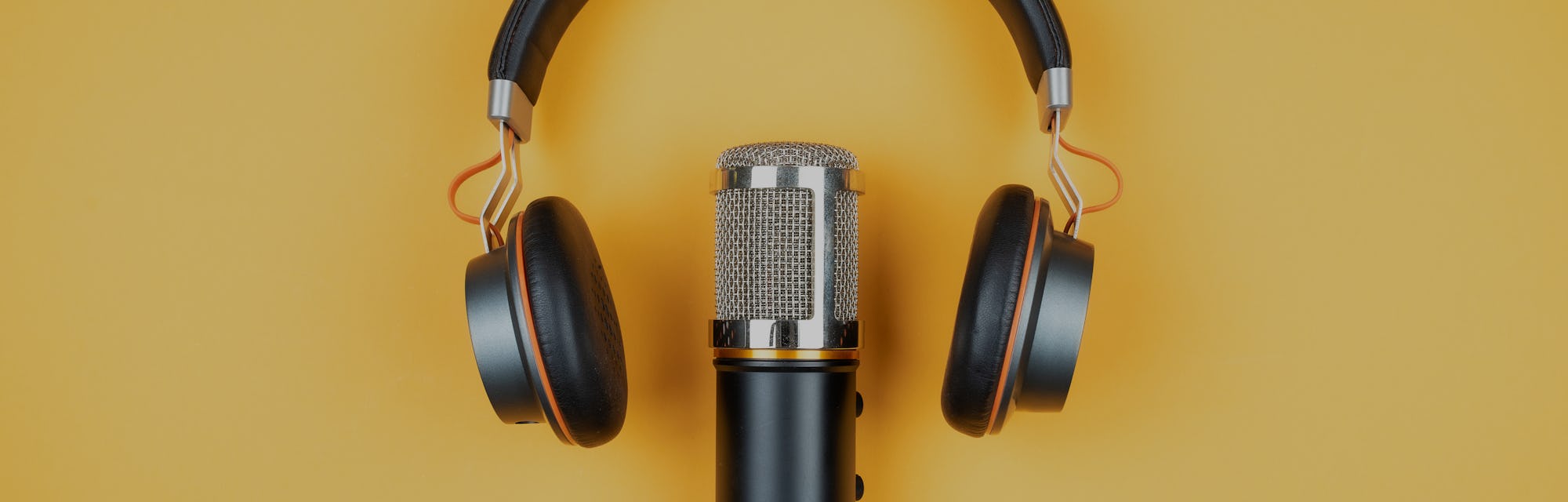 podcasting concept, directly above view of headphones and recording microphone on orange background