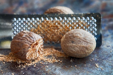 Making nutmeg powder process. Nuts silver grater. Kitchen still life photo. Shallow depth of field, ...