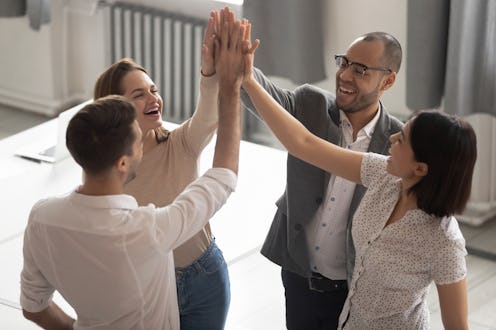 Happy motivated diverse business work team people employees group giving high five together engaged ...