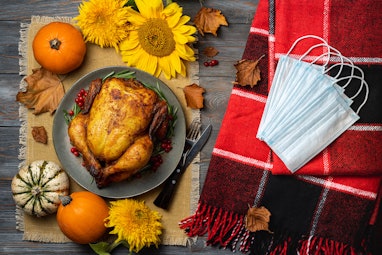Roasted chicken or turkey for Thanksgiving Day, red blanket, autumn decorations, protective mask, to...
