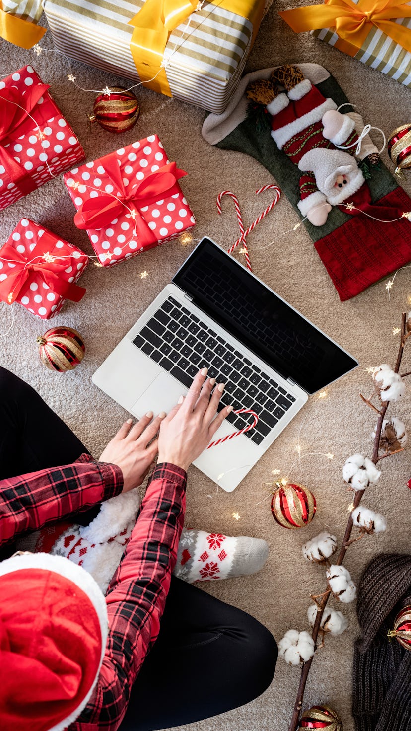 Top view of woman shopping online at christmas holidays holding a present. Christmas online shopping