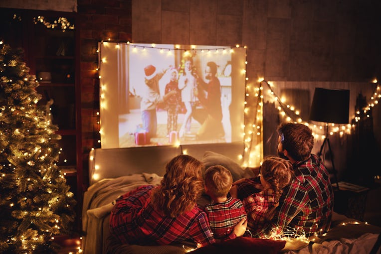 happy family in checkered pajamas: mother father and children watching projector, film, movies with ...