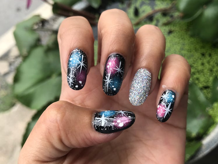 Galaxy nail design with a glitter accent polish on the ring finger.