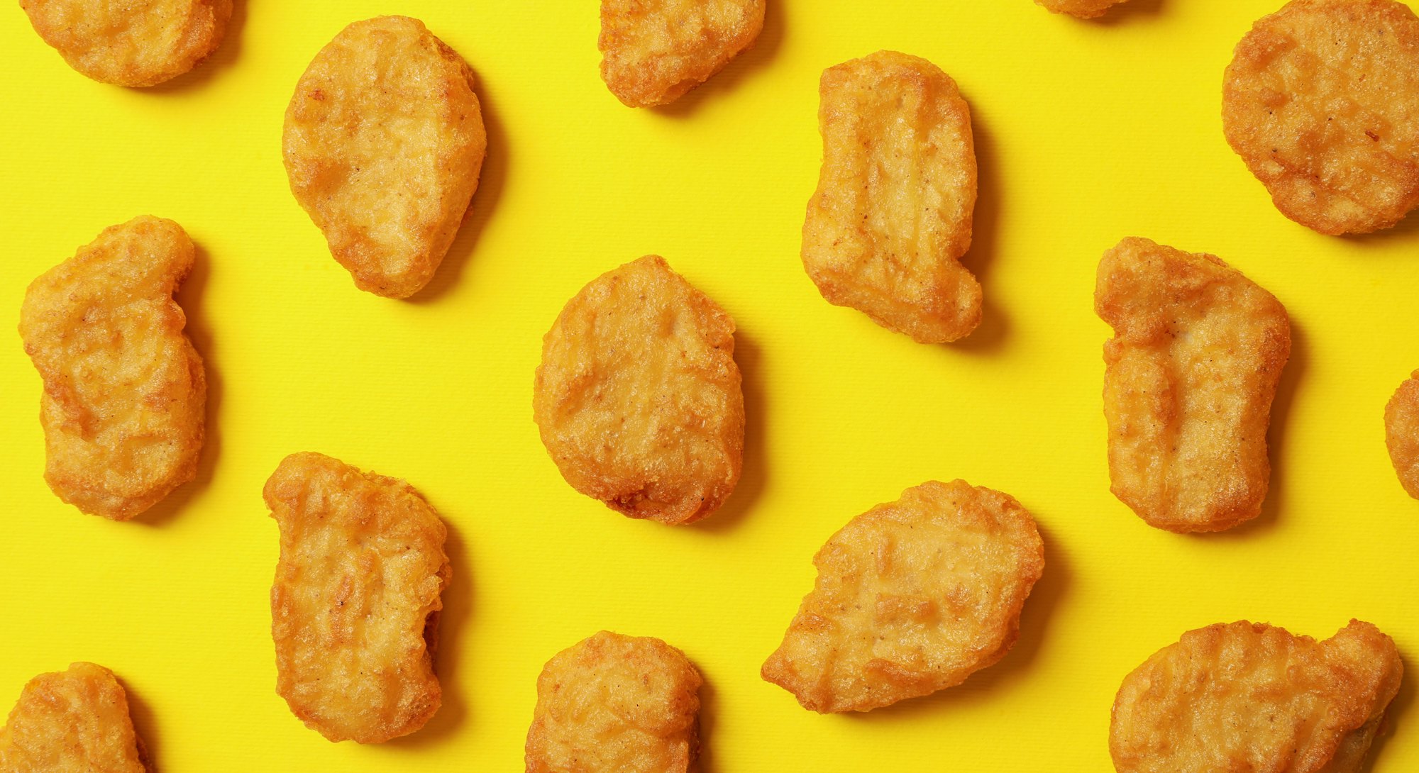 Flat lay with fried chicken nuggets on yellow background
