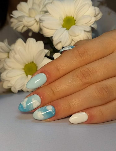 A cloud manicure design with sky blue color, almond shaped nails.