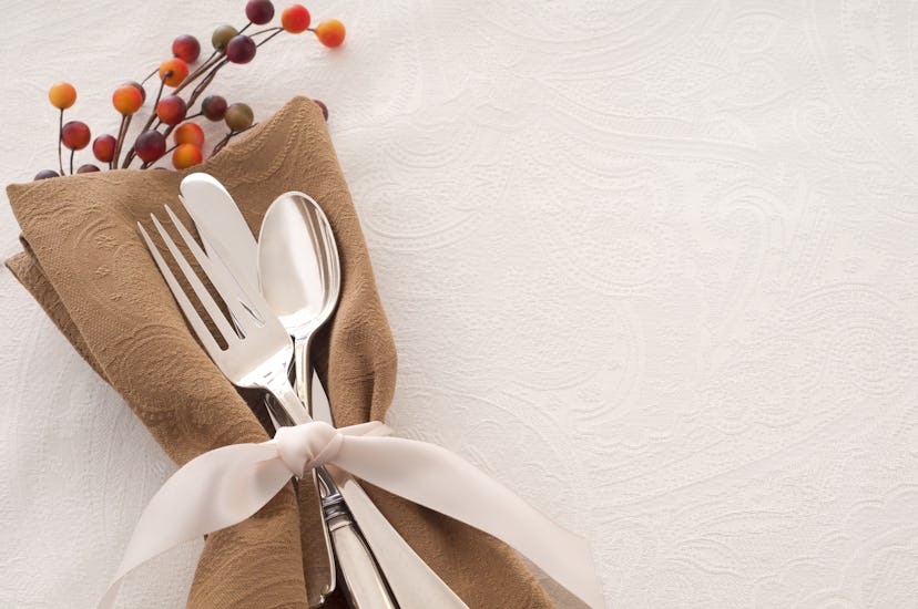 Image of a brown napkin and silverware place setting tied together with an ivory ribbon. 