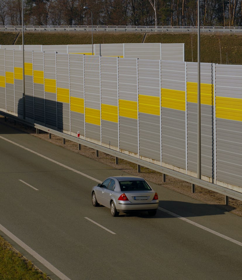 Road transport. Truck and passenger car moving along the highway protected by sound barriers.