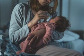 Mother holds her two moths old baby taking care of her at home - Caucasian woman with her newborn ch...