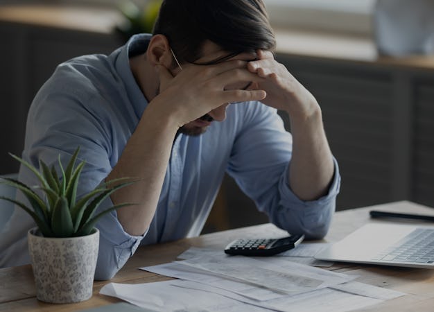 Distressed young Caucasian man sit at desk paying bills feel stressed having financial problems. Unh...