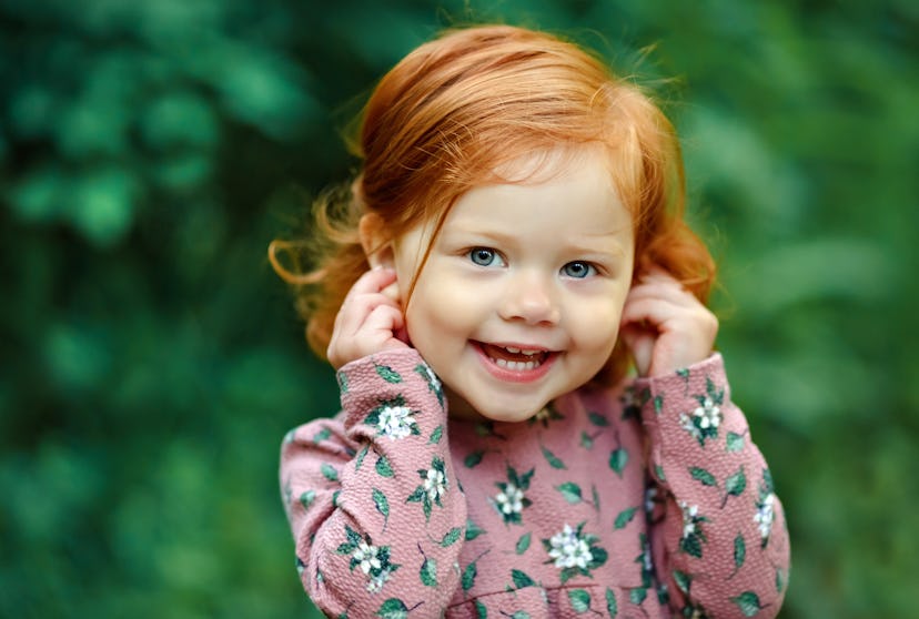 Little girl with red hair smiles to camera in a story about Capricorn names.