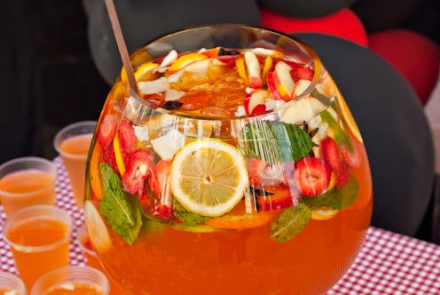 Fruit punch in a large glass bowl. Drink with a variety of fruits close up. Orange alcoholic cocktai...