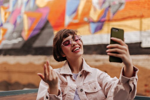 A woman wearing sunglasses is taking a selfie in front of a colorful wall. Leo's biggest weaknesses ...