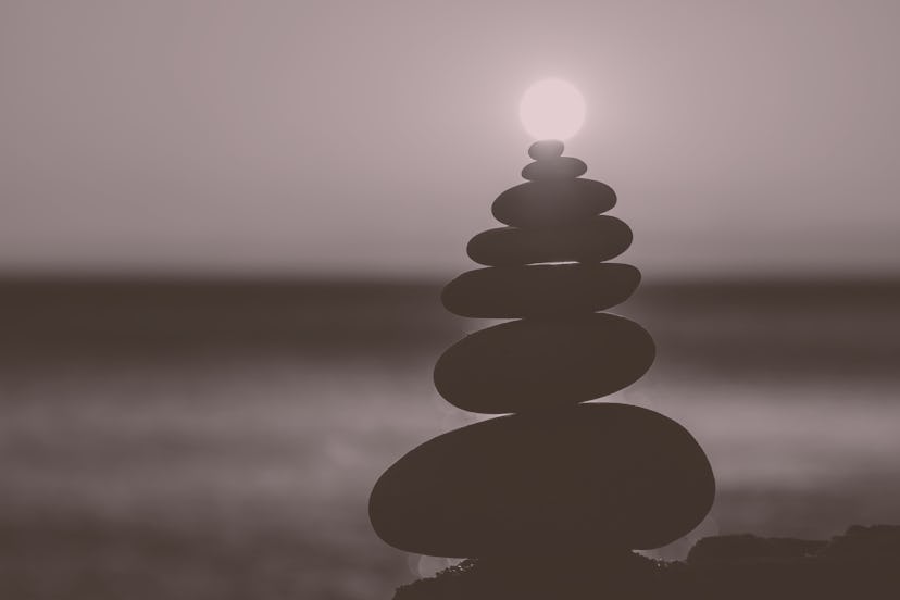 Balanced pebble pyramid silhouette on the beach with the sunset in the background