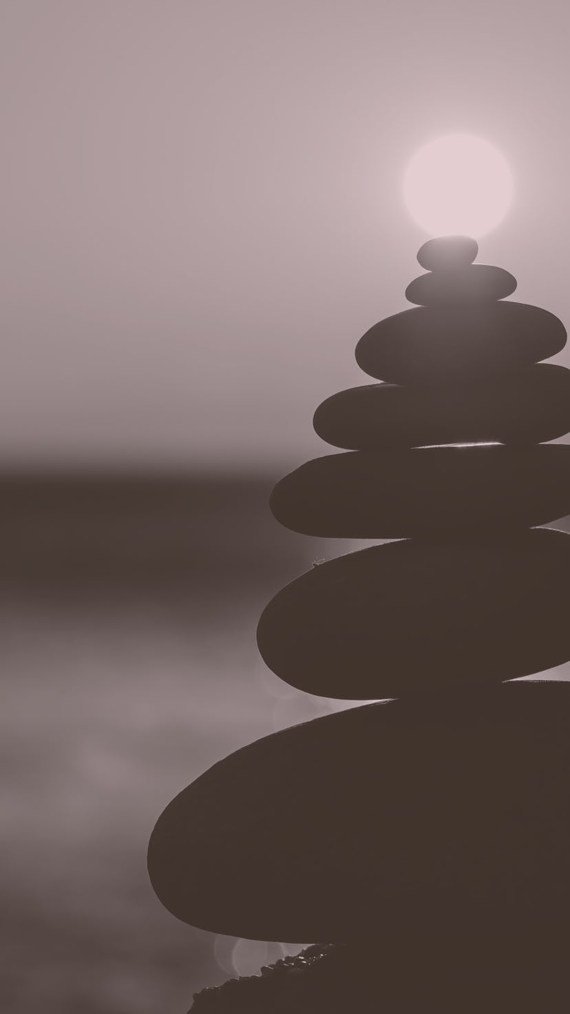 Balanced pebble pyramid silhouette on the beach with the sunset in the background