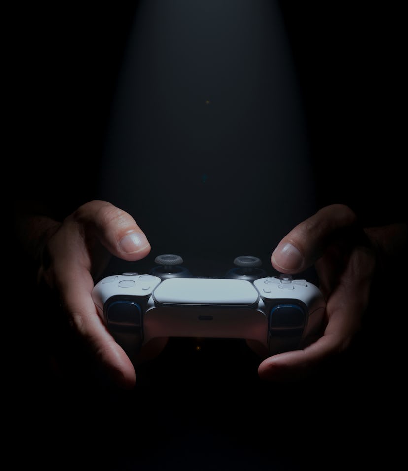 Hands holding a PS5 game controller with spot light.