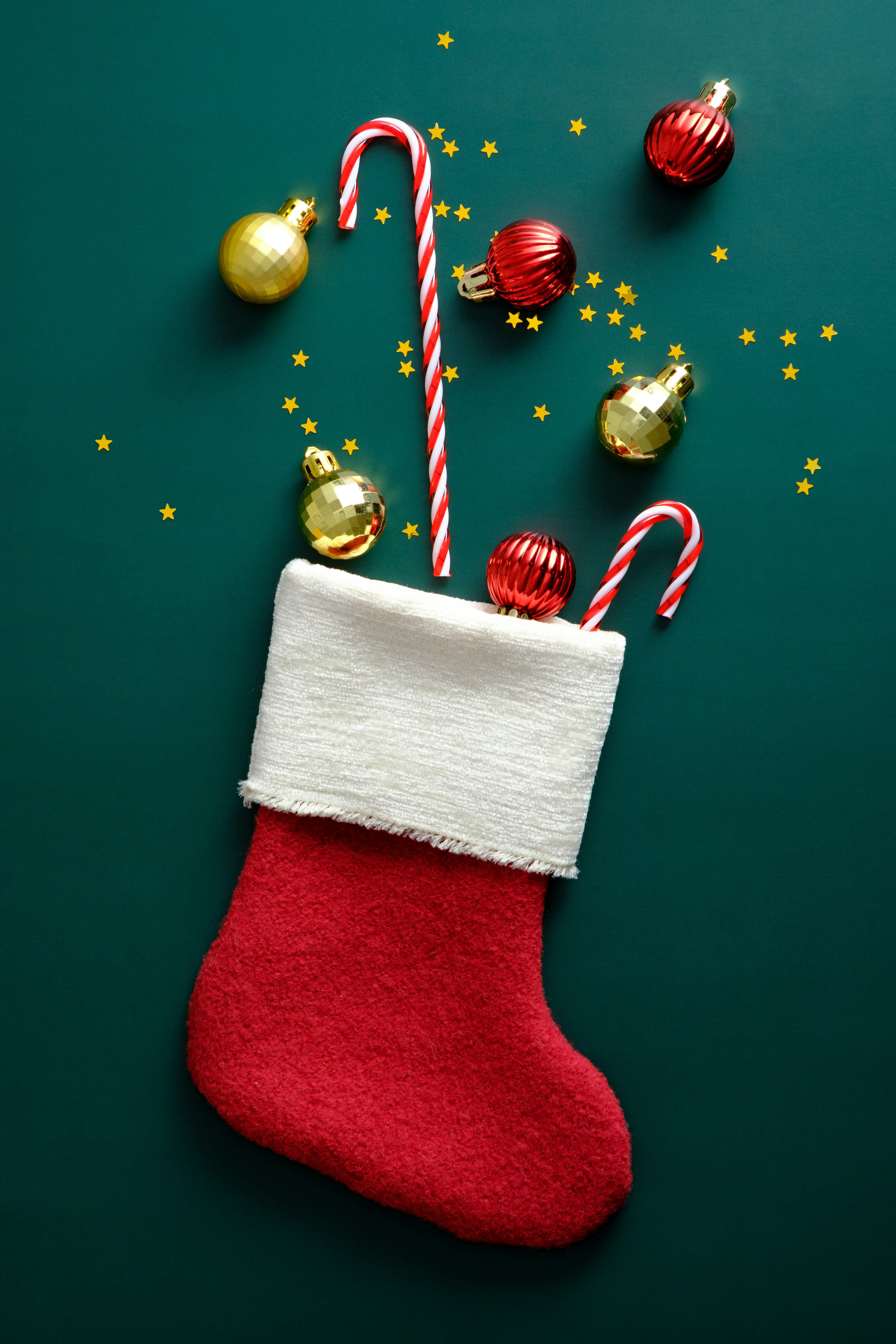 Christmas stocking decorated candy canes, golden and red balls, confetti on vintage green background
