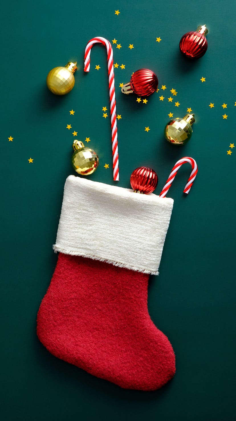 Christmas stocking decorated candy canes, golden and red balls, confetti on vintage green background