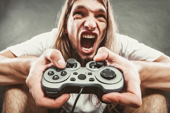 Addiction. Stressed depressed young man playing gaming on pad. Angry guy with controller pad play co...