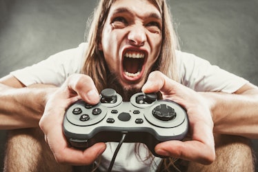 Addiction. Stressed depressed young man playing gaming on pad. Angry guy with controller pad play co...