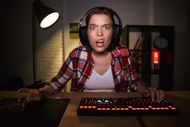 Nervous angry young woman gamer playing online computer games at the table