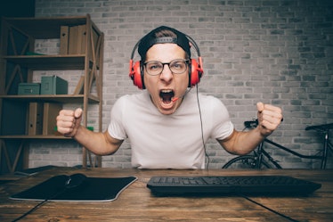 Young man playing game at home and streaming playthrough or walkthrough video. Stylish boy screaming...