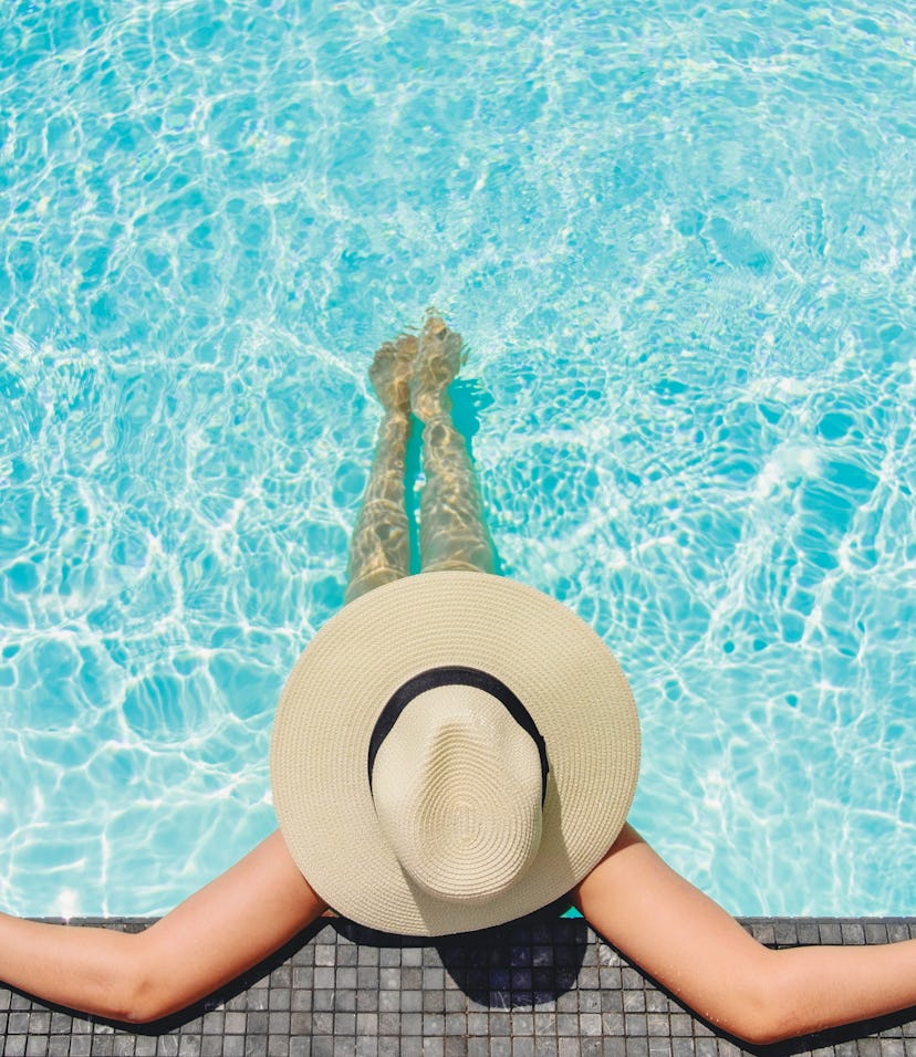 woman wearing a big brimmed hat relaxing in the pool
