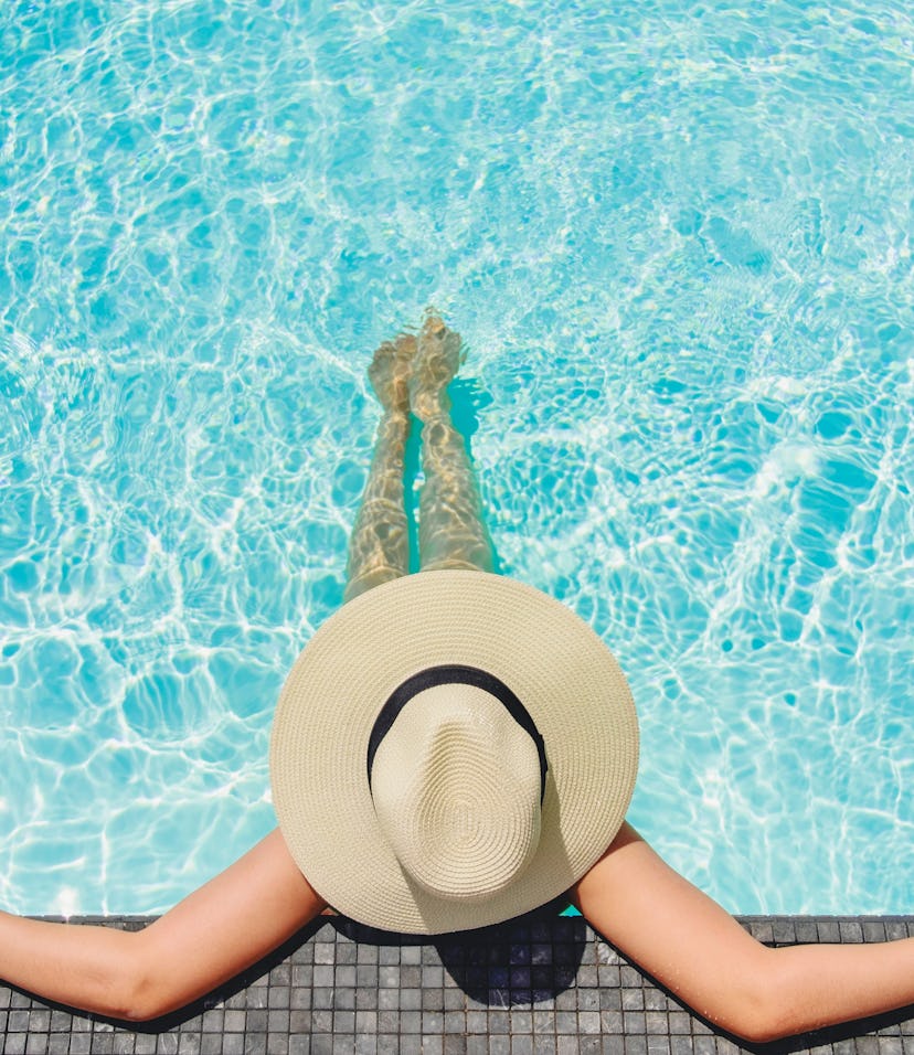 woman wearing a big brimmed hat relaxing in the pool 