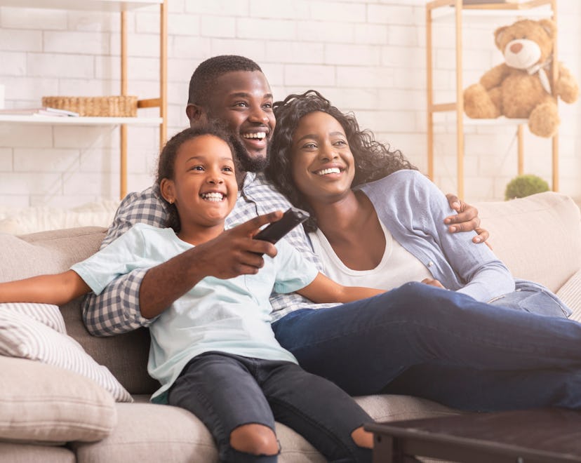 Happy african american family relaxing and watching tv at home, enjoying weekend together.