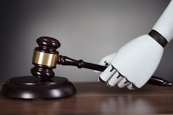 Close-up Of Robot's Hand Hitting Gavel At Wooden Desk