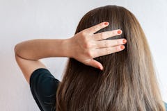 Rear view of young Asian woman touching her thick hair. Thick hair technically refers to the width o...