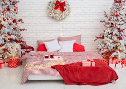 Cozy Decorated bedroom for Christmas holidays with tree and gifts. Spacious white light bedroom in a...