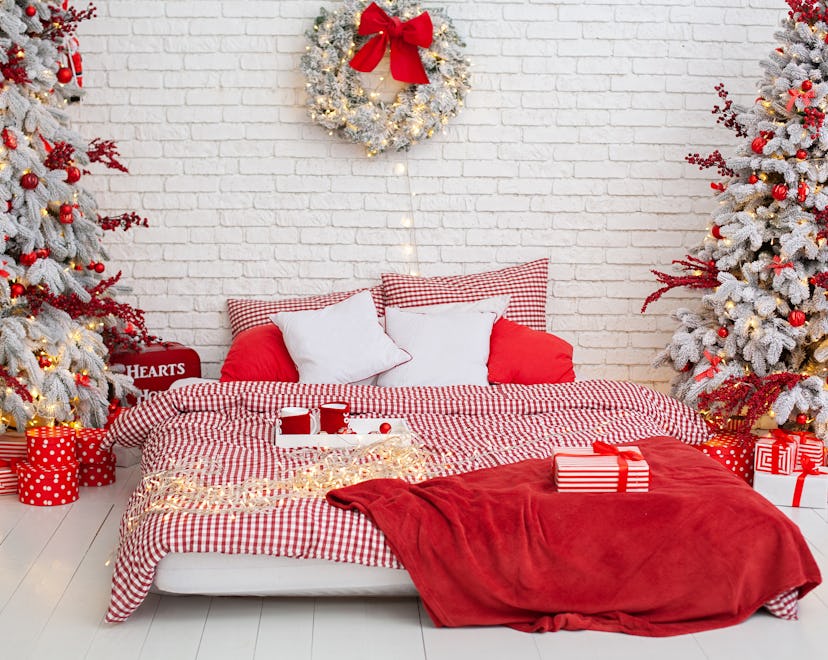 Cozy Decorated bedroom for Christmas holidays with tree and gifts. Spacious white light bedroom in a...