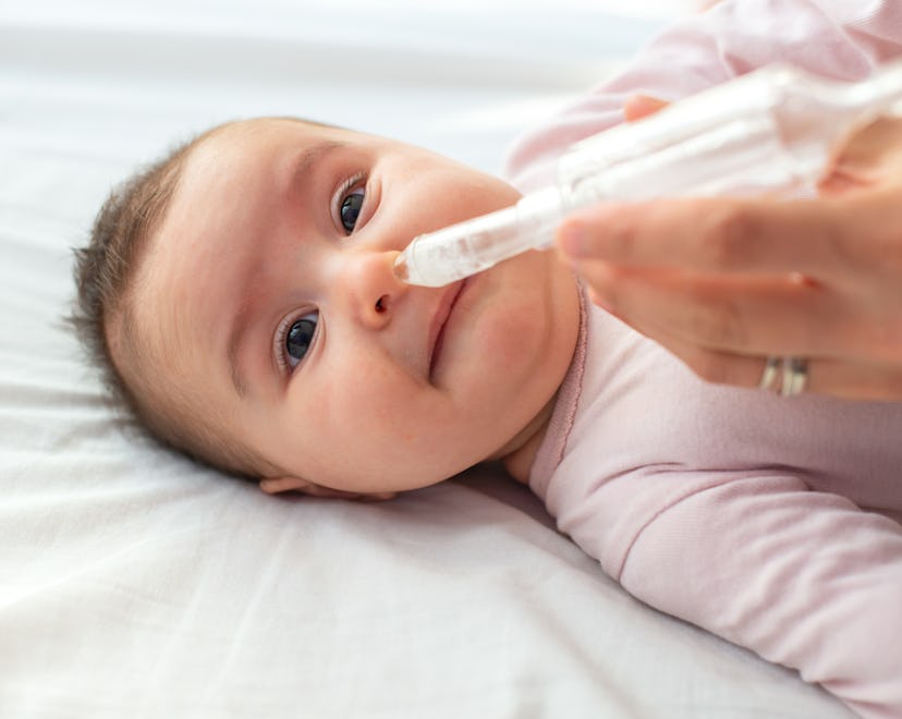 Mother using baby nasal aspirator mucus nose suction