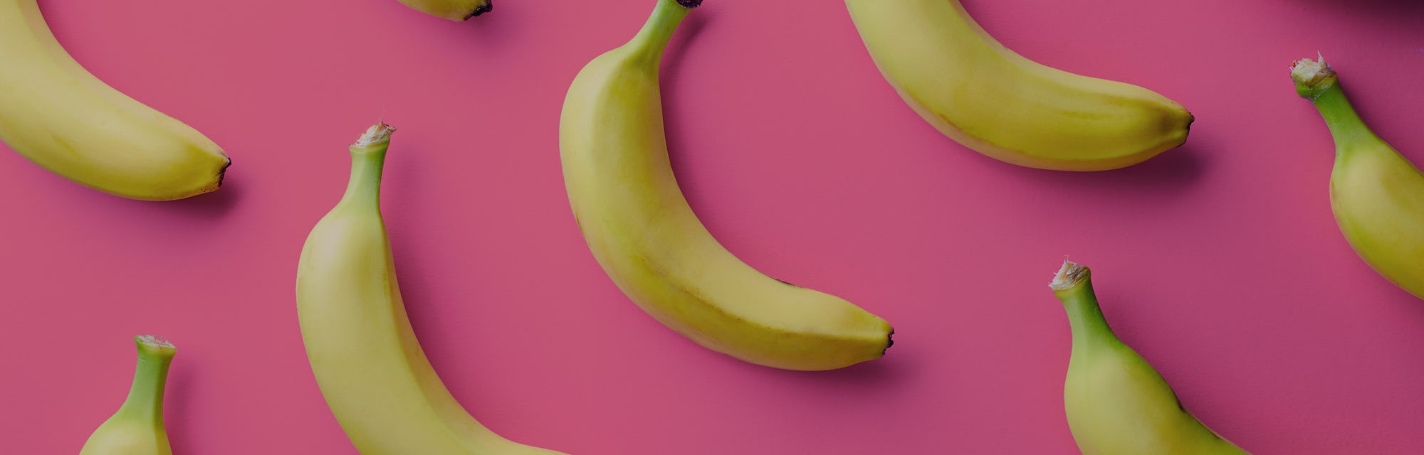 Colorful fruit pattern of fresh yellow bananas on pink background. From top view