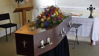 closeup shot of a funeral casket in a hearse or chapel or burial at cemetery
