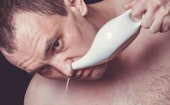 Close up portrait of a man cleaning his nose using white ceramic neti pot