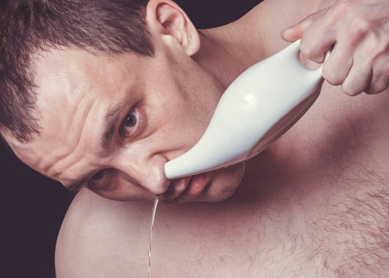 Close up portrait of a man cleaning his nose using white ceramic neti pot