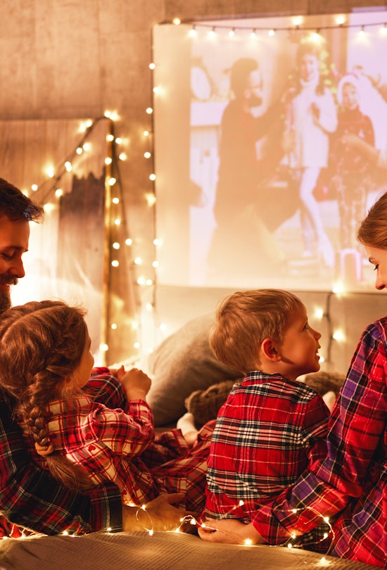 happy family in checkered pajamas: mother father and children watching projector, film, movies with ...