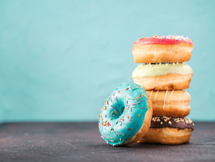 Stack of assorted donuts on black and blue cement background. Blue glazed doughnut with sprinkles on...