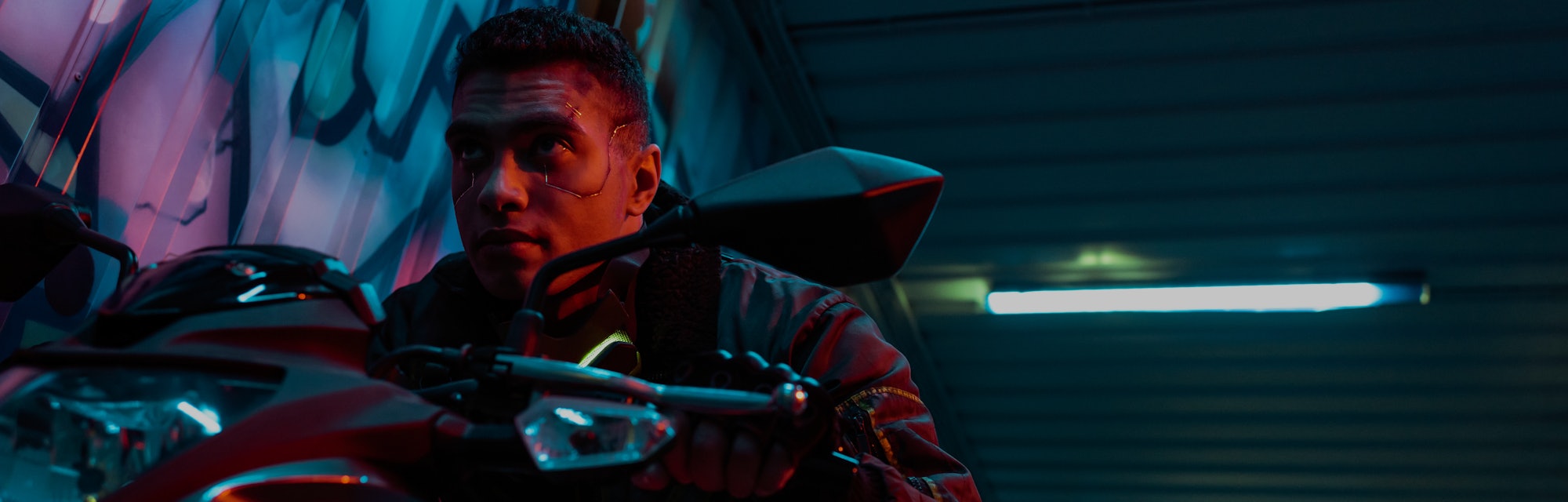 low angle view of handsome and mixed race cyberpunk player riding motorcycle