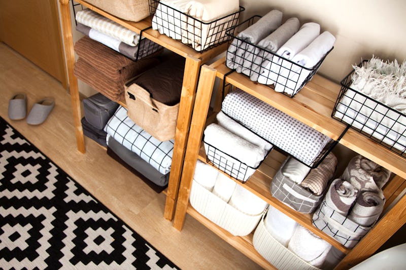 Spring cleaning of closet. Vertical tidying up storage. Neatly folded bed sheets in the metal black ...