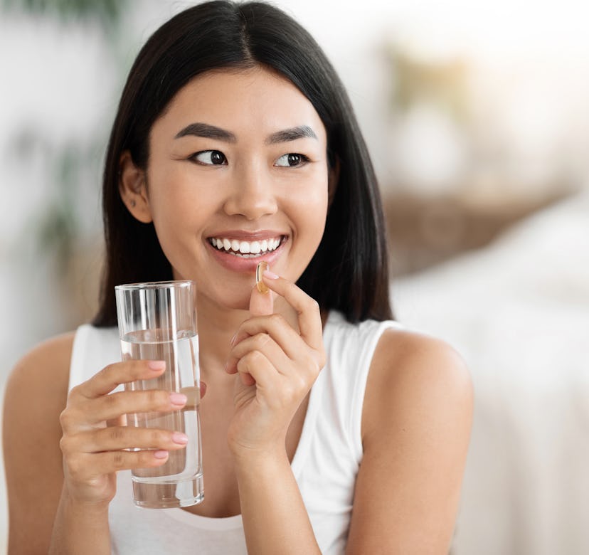 Diet, nutrition, healthy eating concept. Close Up Of Happy Smiling Asian Woman Taking Supplement Pil...