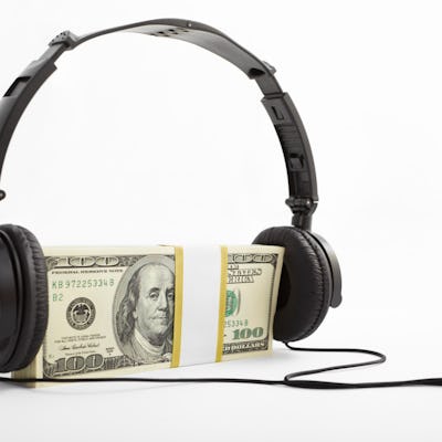 A stack of US$100 bills with headphone put on, over white background