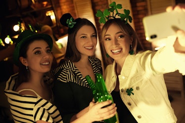 A group of friends pose for a selfie with some beer in a bar on St. Patrick's Day. 