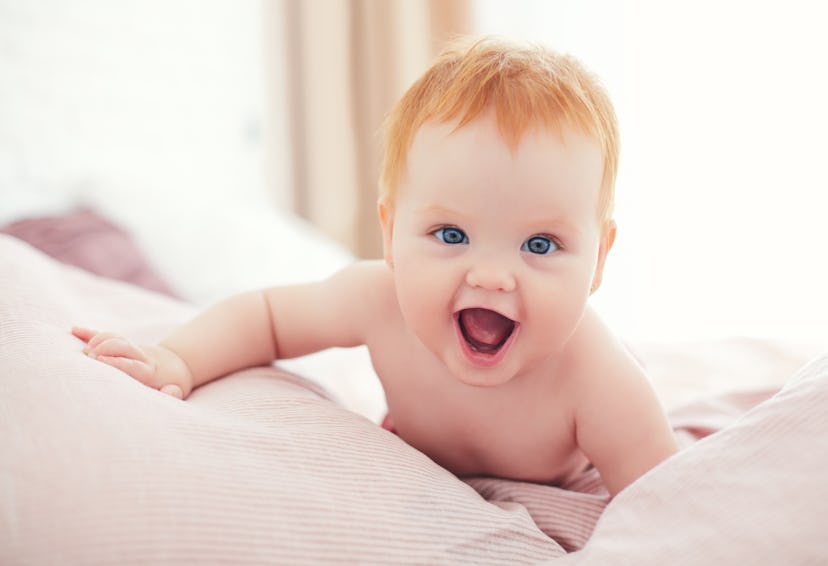 happy excited infant baby girl crawling on the bed in a list of girl names that start with L