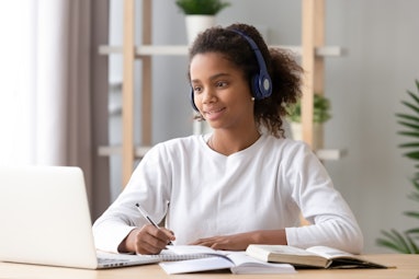 African teen girl wearing headphones study with internet chat skype teacher prepare for exam, black ...