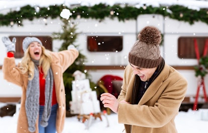 Snowball Fight. Romantic couple having fun outdoors, throwing snow at each other and laughing during...