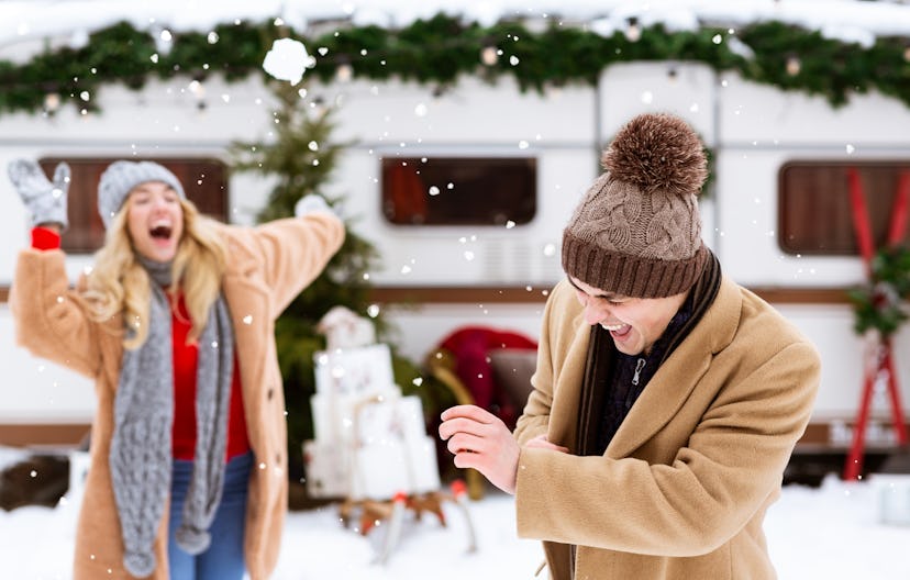 Snowball Fight. Romantic couple having fun outdoors, throwing snow at each other and laughing during...