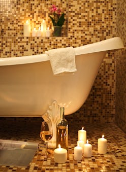 Home bathroom interior with bubble bath, candles, magazine and white whine. Relax concept